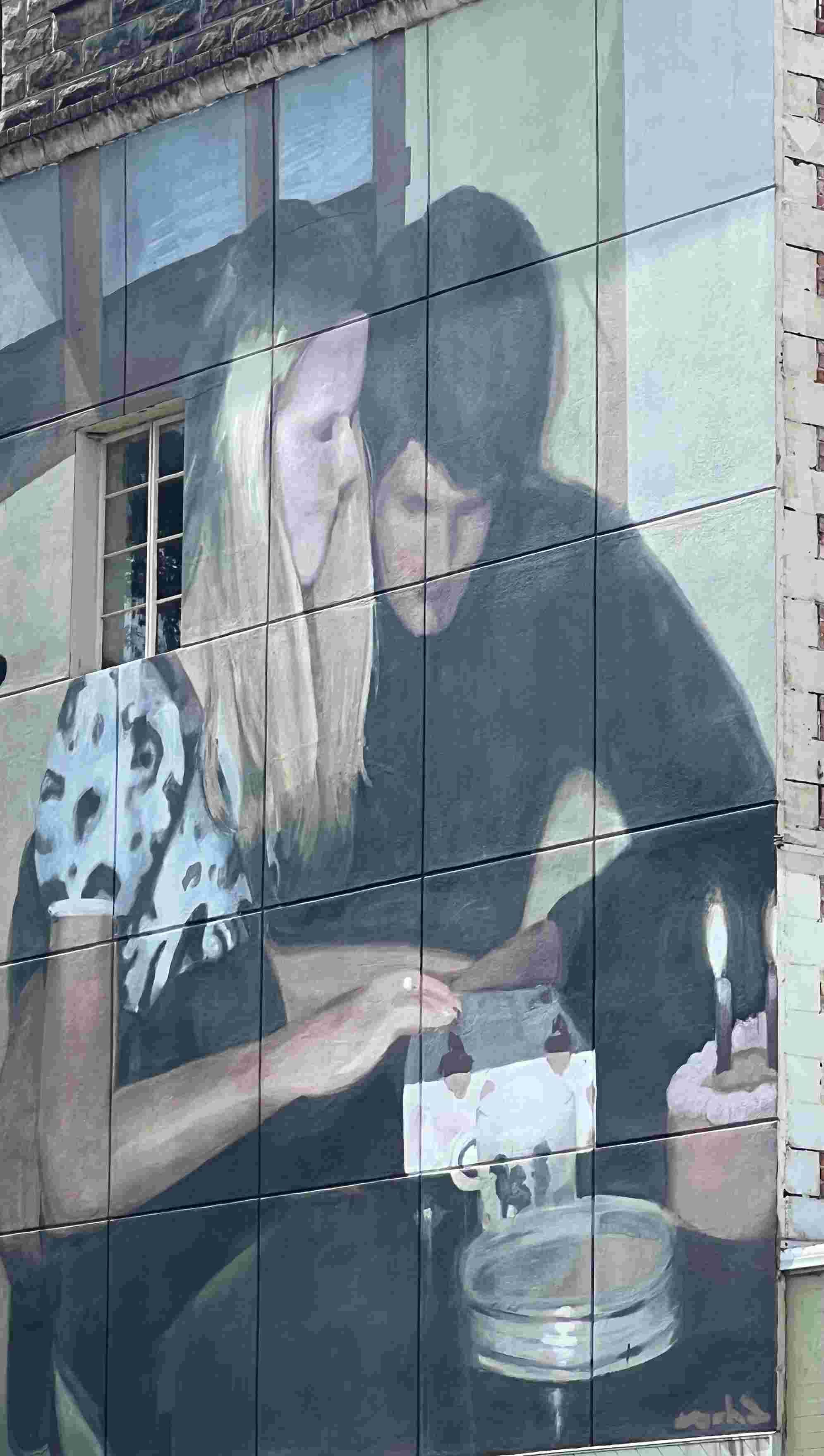 Blonde girl and boyfriend sharing a box which is probably a present and a pink cake with lighted candles